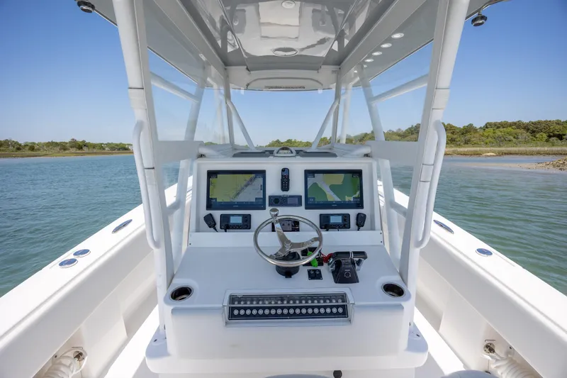 Slide: The Image of 2019 Invincible 36 Open Fisherman boat console with navigation screens on calm water. - 18