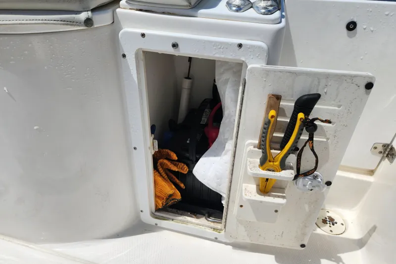 Slide: The Image of Storage compartment on a 2001 Cobia 234 Center Console boat with tools and gloves. - 15