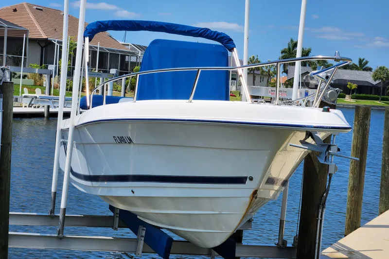 Slide: The Image of 2001 Cobia 234 Center Console boat docked by waterfront homes. - 2