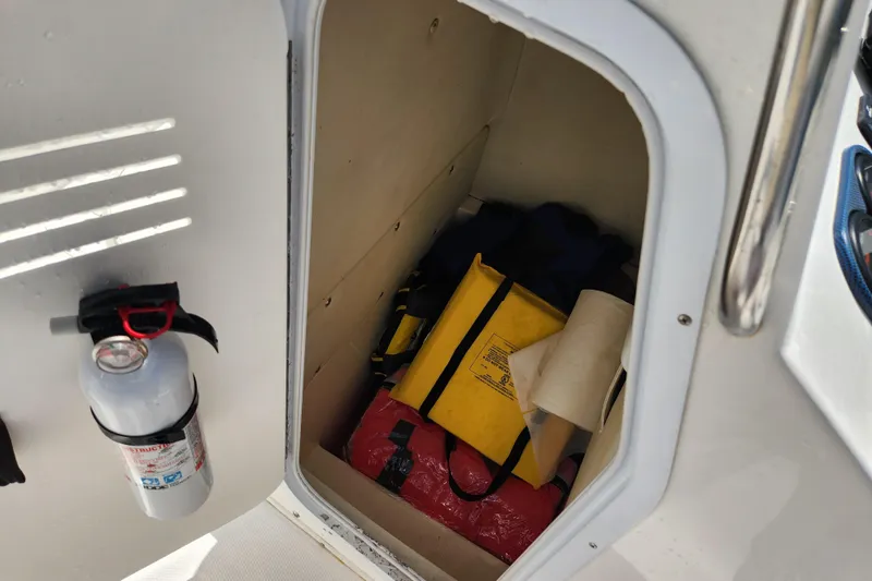 Slide: The Image of Storage compartment on a 2001 Cobia 234 Center Console with safety equipment and fire extinguisher. - 20