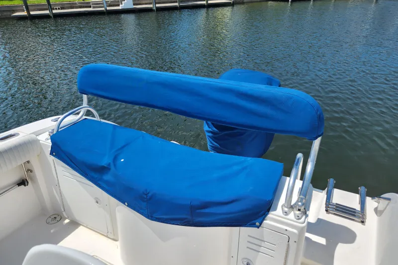 Slide: The Image of 2001 Cobia 234 Center Console boat with blue seating cover by the water. - 23