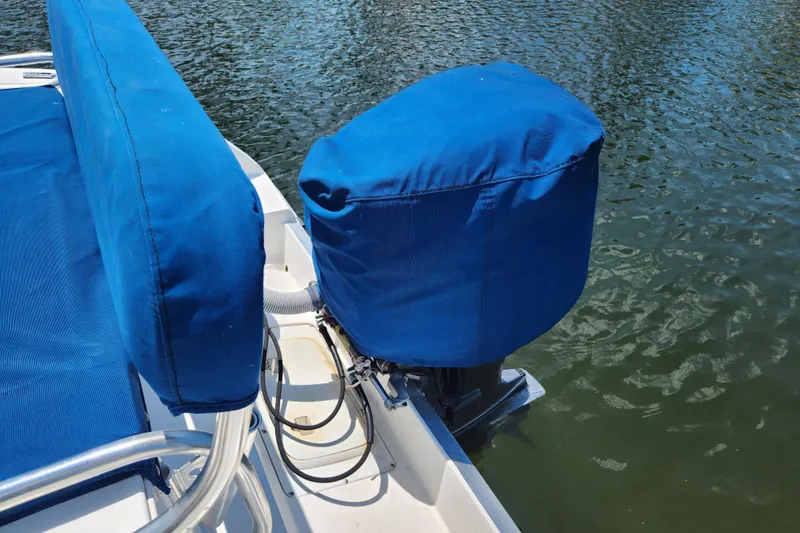 Slide: The Image of Blue-covered motor and seating on 2001 Cobia 234 Center Console boat by the water. - 24