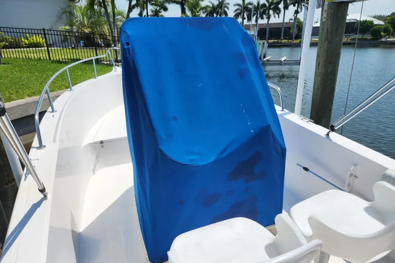 Slide: The Image of 2001 Cobia 234 Center Console boat with blue cover, docked by a waterfront. - 25