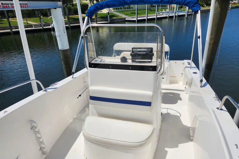 Slide: The Image of 2001 Cobia 234 Center Console boat with blue canopy, docked by the water. - 5