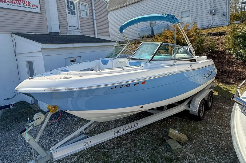 The Image of 2022 Robalo R227 Dual Console boat on trailer, parked outside a marine center. - 0