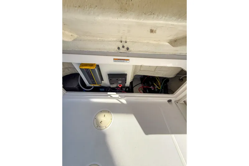 Slide: The Image of 2022 Robalo R227 Dual Console boat interior showing storage compartment and electrical components. - 23
