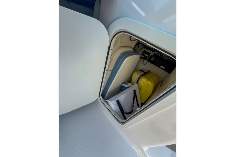 Slide: The Image of Storage compartment of 2022 Robalo R227 Dual Console boat with various items inside. - 25