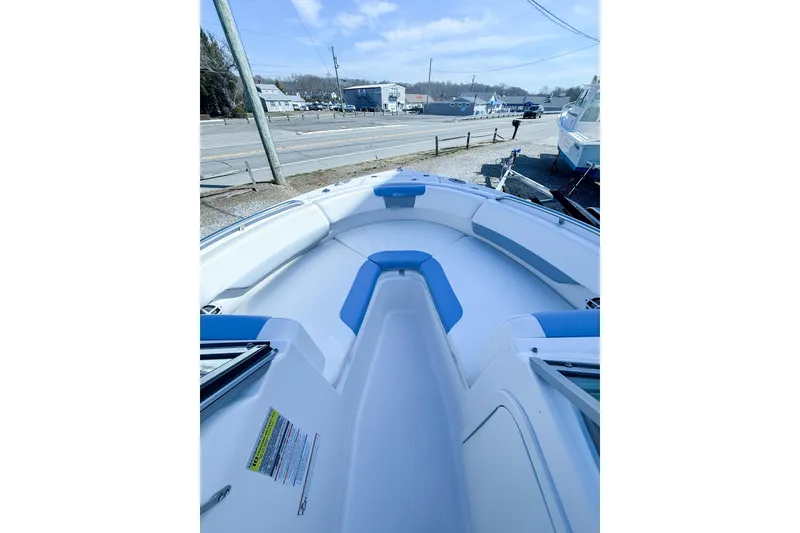 Slide: The Image of 2022 Robalo R227 Dual Console boat with blue and white seating, docked near a road. - 26