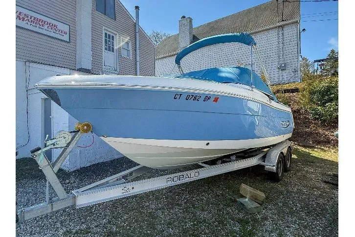 Slide: The Image of 2022 Robalo R227 Dual Console boat on trailer, blue and white exterior, parked outdoors. - 7