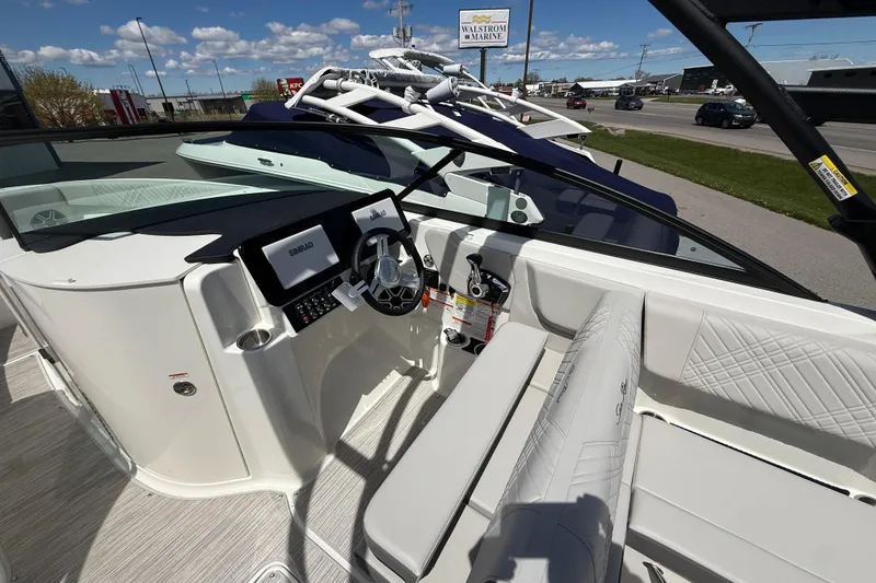 Slide: The Image of 2026 Sea Ray SDX 250 boat interior with steering wheel and seating, under clear blue sky. - 11