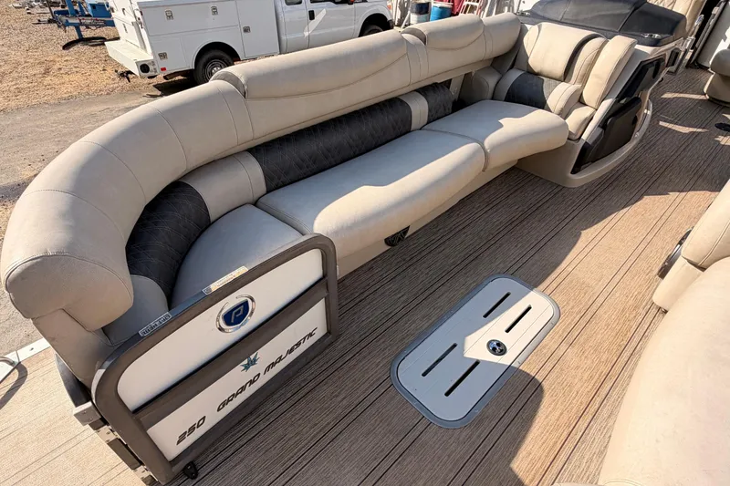 Slide: The Image of Premier 250 Grand Majestic 2021 pontoon boat interior with plush seating and wood-style flooring. - 7