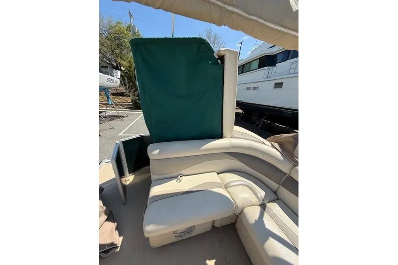 Slide: The Image of Sweetwater 2086 BW 2015 boat interior with beige seating and green privacy curtain. - 7