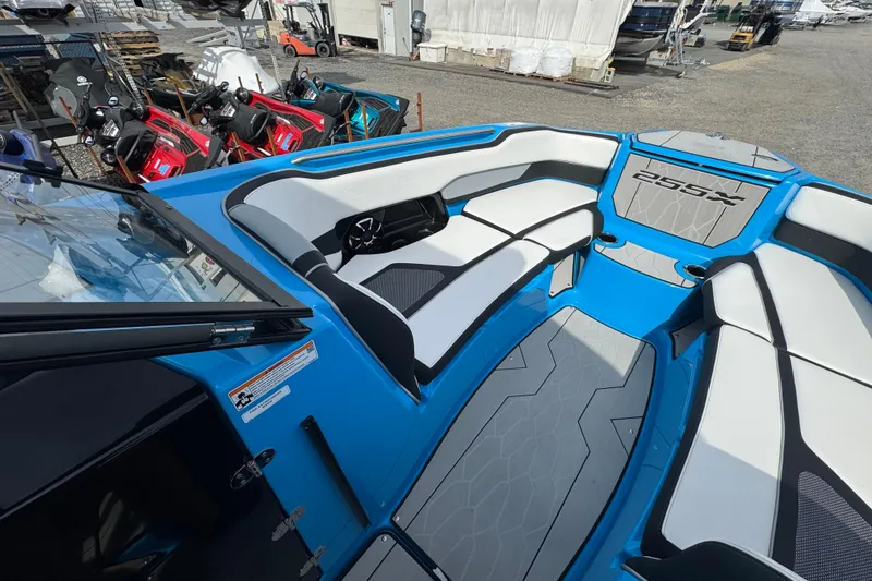 Slide: The Image of 2022 Yamaha Boats 255XD interior with blue and white seating, docked near other vehicles. - 10