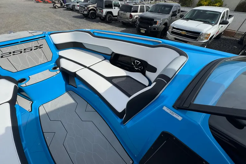 Slide: The Image of 2022 Yamaha Boats 255XD interior with blue and gray seating, parked vehicles in background. - 12