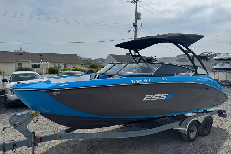 Slide: The Image of 2022 Yamaha Boats 255XD in blue and gray on a trailer, parked outdoors. - 4