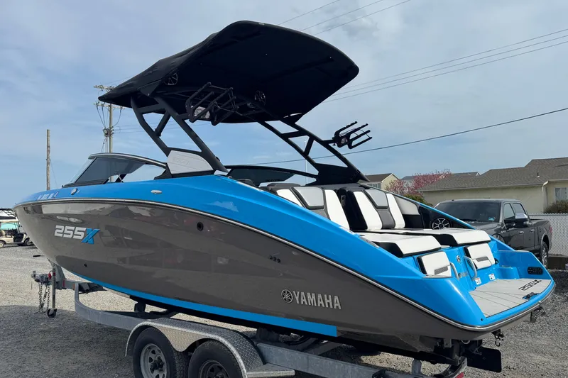 Slide: The Image of 2022 Yamaha Boats 255XD in blue and gray on a trailer, parked outdoors. - 6