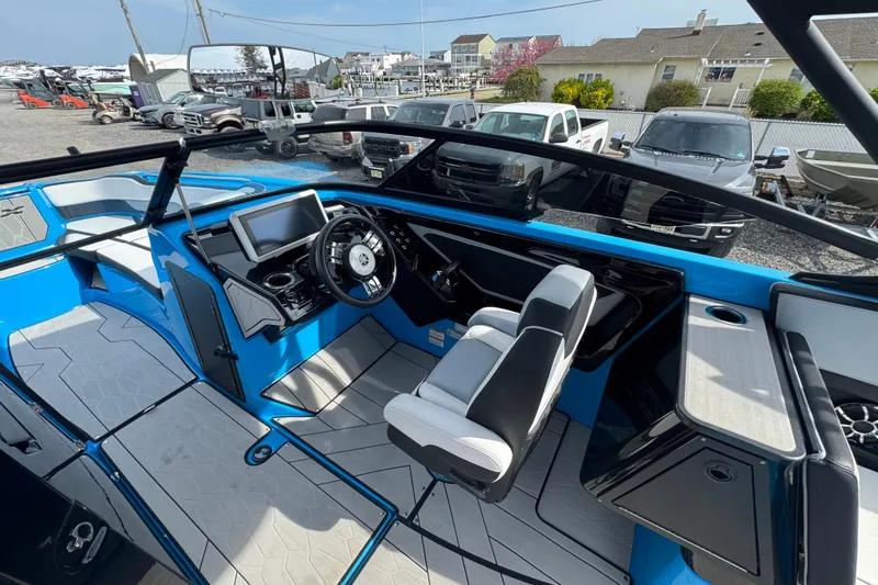 Slide: The Image of 2022 Yamaha Boats 255XD interior with modern dashboard and seating, parked outdoors. - 8