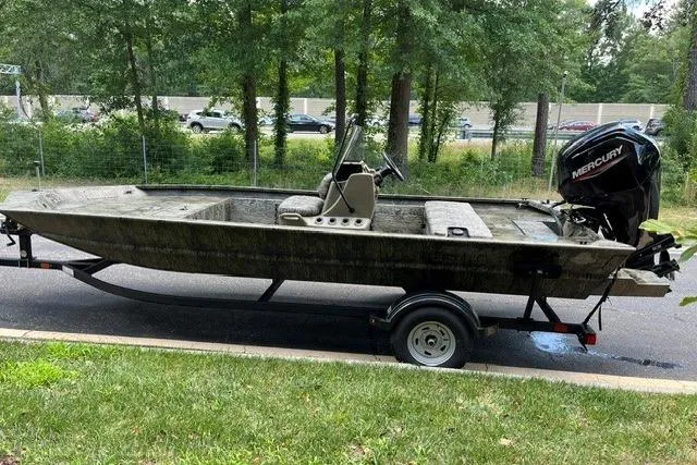 Slide: The Image of 2026 Tracker Grizzly 1860 CC boat on trailer, parked near a wooded area. - 2
