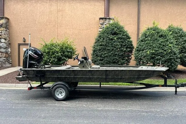 The Image of 2026 Tracker Grizzly 1860 CC boat on trailer, parked outdoors near shrubs. - 0