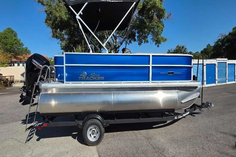 Slide: The Image of 2026 Sun Tracker Party Barge 18 DLX pontoon boat with blue exterior, parked outdoors. - 1