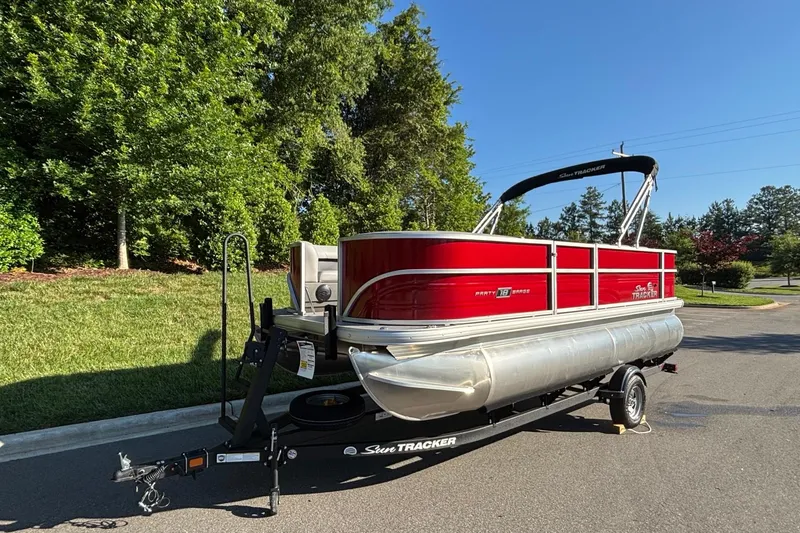 Slide: The Image of 2026 Sun Tracker Party Barge 18 DLX pontoon boat on trailer, parked outdoors. - 2