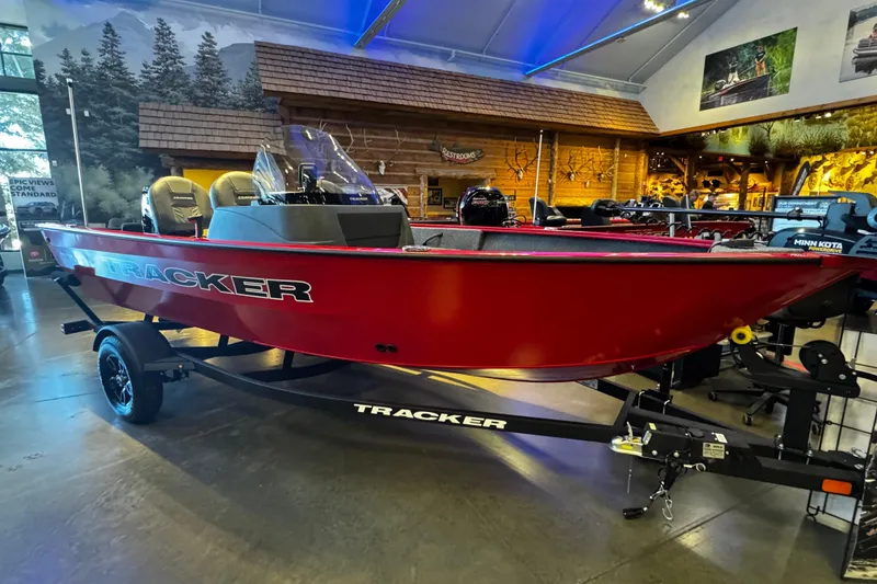 Slide: The Image of 2026 Tracker Pro Guide V-16 SC boat in showroom, vibrant red exterior, on trailer. - 2