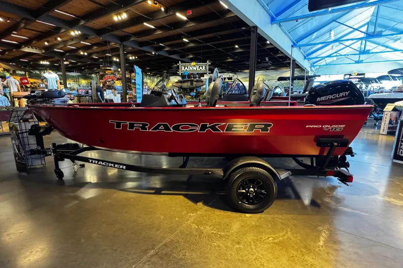 The Image of 2026 Tracker Pro Guide V-16 SC boat displayed indoors, featuring a red exterior and Mercury engine. - 0