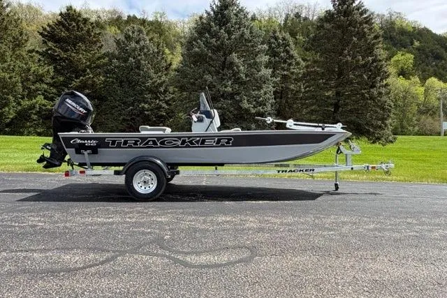 Slide: The Image of 2026 Tracker Bass Tracker Classic CC boat on trailer, parked outdoors with trees in background. - 2