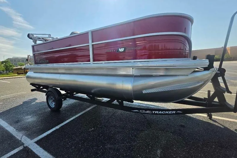 The Image of 2026 Sun Tracker Party Barge 18 DLX pontoon boat on trailer in parking lot. - 0