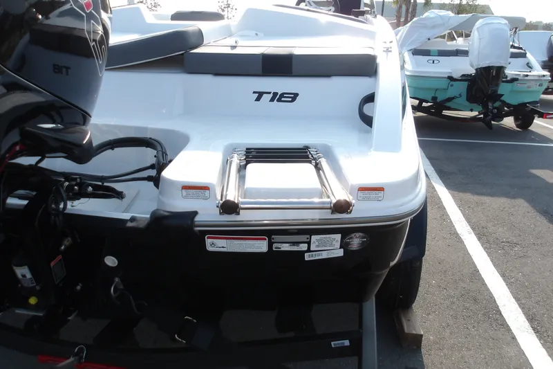 Slide: The Image of 2026 Tahoe T18 boat rear view with motor and swim ladder. - 18