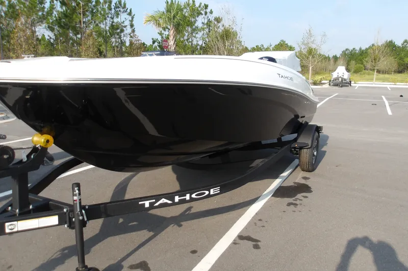 Slide: The Image of 2026 Tahoe T18 boat on trailer in parking lot, surrounded by trees. - 2