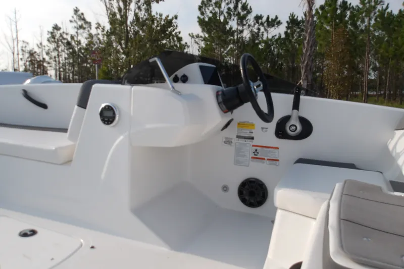 Slide: The Image of 2026 Tahoe T18 boat interior with steering wheel and seating, surrounded by trees. - 8