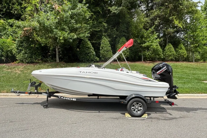 The Image of 2026 Tahoe T16 boat on trailer, parked outdoors with lush greenery background. - 0
