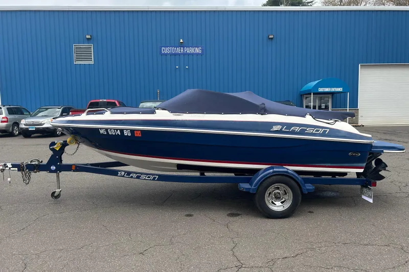 Slide: The Image of 2017 Larson LX 185S I/O boat on trailer, parked outside blue building. - 11