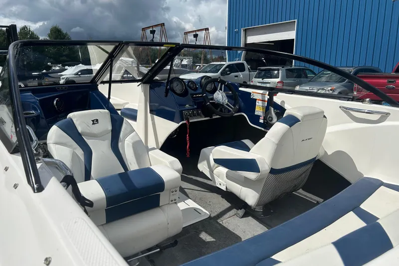 Slide: The Image of 2017 Larson LX 185S I/O boat interior with blue and white seating, parked outdoors. - 18