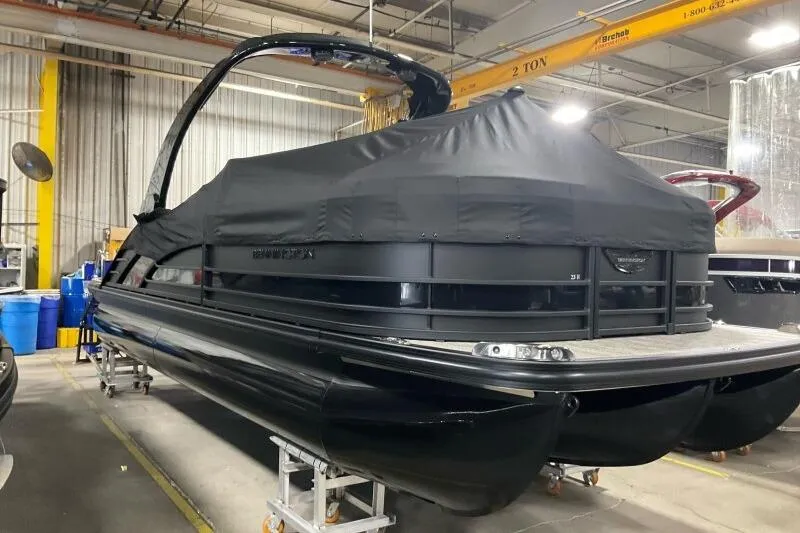 Slide: The Image of 2026 Bennington R 23 RSBA pontoon boat covered in black tarp in a warehouse. - 14