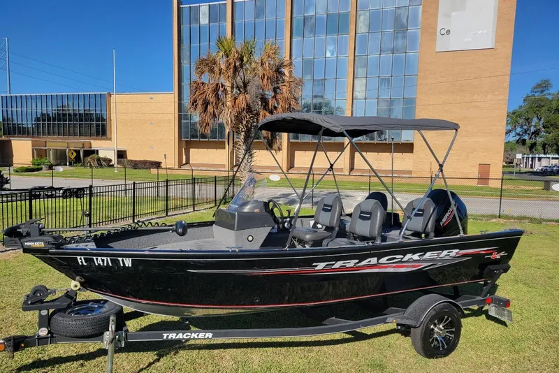 The Image of 2020 Tracker Pro Guide V-16 SC boat on trailer, parked outdoors near a building. - 1
