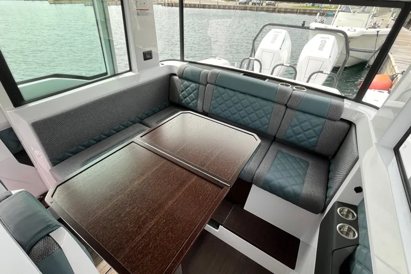 Slide: The Image of 2024 Axopar 37 XC Cross Cabin interior with elegant seating and wooden table. - 14