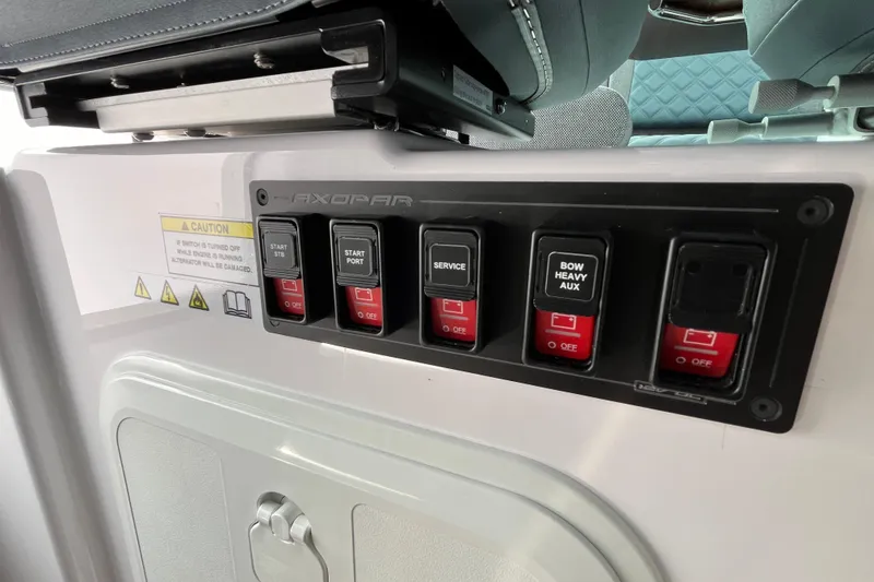 Slide: The Image of Control panel of 2024 Axopar 37 XC Cross Cabin with labeled switches and caution sign. - 20