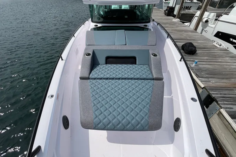 Slide: The Image of 2024 Axopar 37 XC Cross Cabin boat with cushioned seating, docked by the water. - 5
