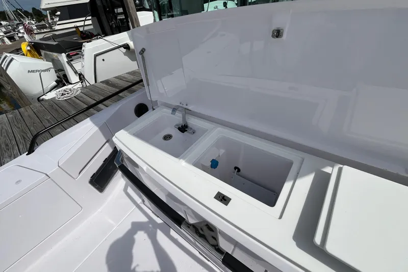 Slide: The Image of 2024 Axopar 37 XC Cross Cabin boat with open storage compartments and sink on deck. - 9