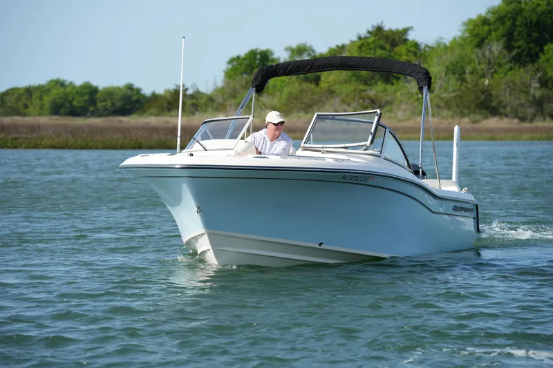 Slide: The Image of 2021 Grady-White Freedom 215 boat cruising on a calm lake with lush greenery. - 5