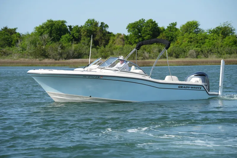 Slide: The Image of 2021 Grady-White Freedom 215 boat cruising on a serene lake with lush greenery. - 7