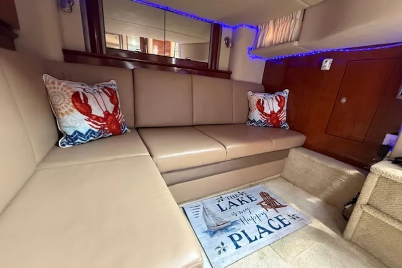 Slide: The Image of Interior of 2004 Sea Ray 390 Sundancer with lobster-themed pillows and cozy seating area. - 12