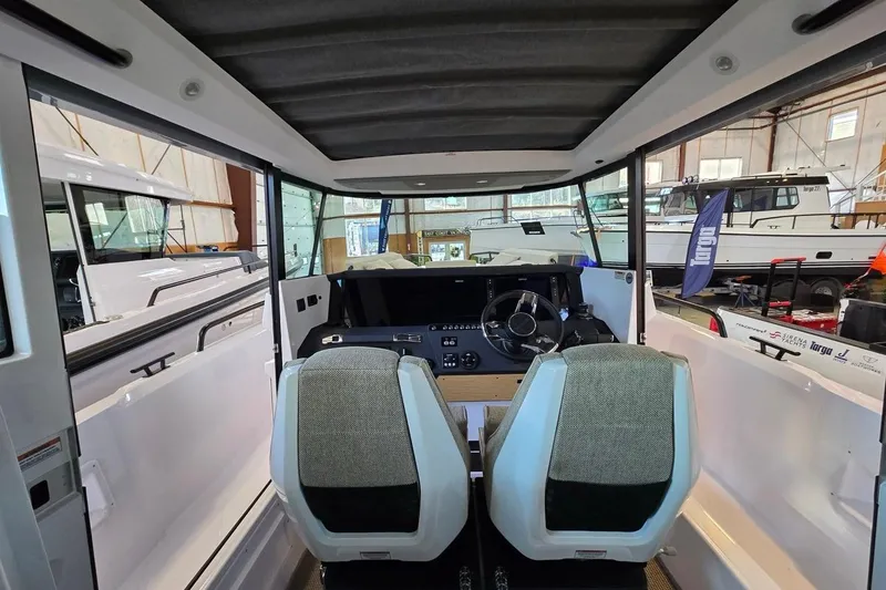 Slide: The Image of 2026 Axopar 29 XC Cross Cabin interior with dual seats and steering wheel in a showroom. - 10
