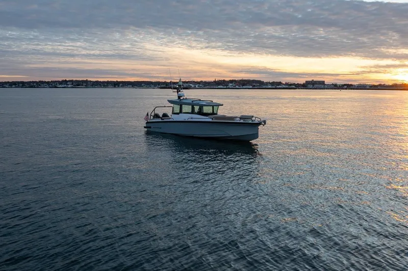 Slide: The Image of 2026 Axopar 29 XC Cross Cabin boat on calm water at sunset. - 2
