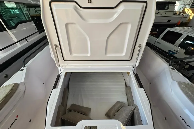 Slide: The Image of 2026 Axopar 29 XC Cross Cabin storage compartment with open lid and cushions inside. - 39