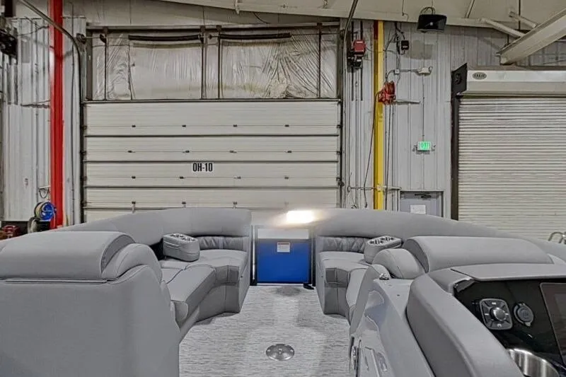 Slide: The Image of 2026 Bennington 23 LXS Swingback interior with gray seating in a warehouse setting. - 16