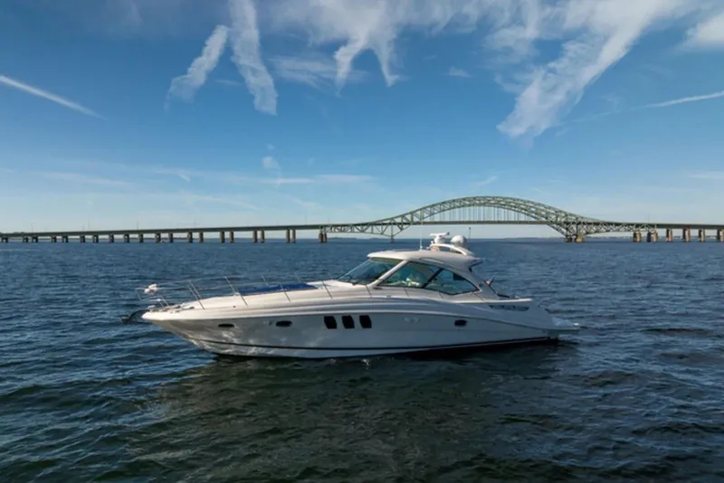 The Image of 2010 Sea Ray 500 Sundancer yacht cruising near a bridge under a clear blue sky. - 0