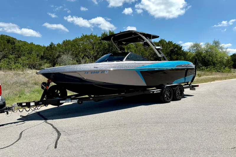 Slide: The Image of 2016 Malibu Wakesetter 25 LSV boat on trailer, parked on a sunny road. - 10